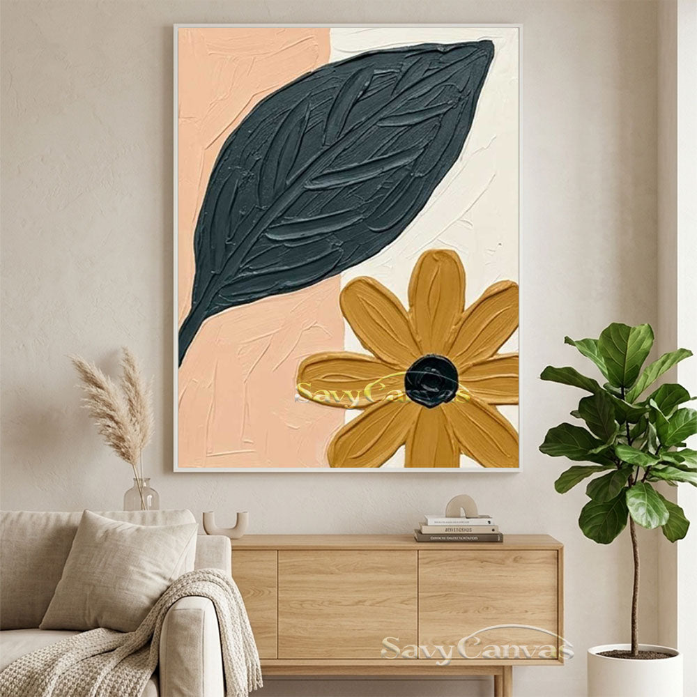 Large hand-painted abstract floral oil painting with a heavy-textured dark green leaf and mustard yellow flower on a pink and cream background, hanging in a modern living room